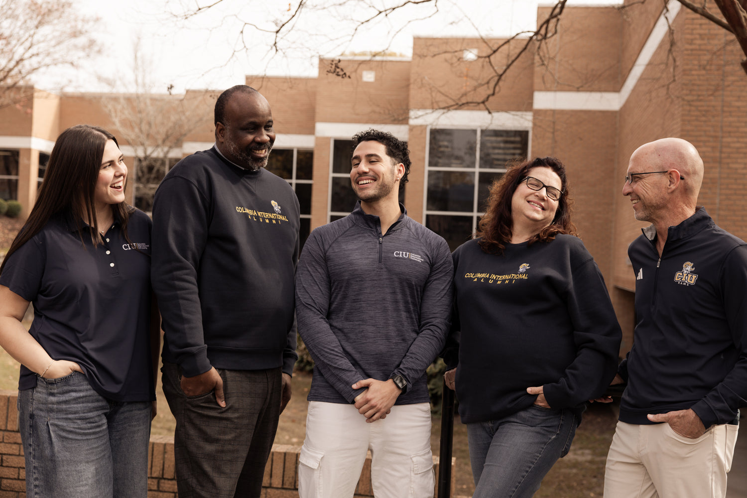 Group of five people wearing professional CIU gear, standing outdoors in front of a brick building.