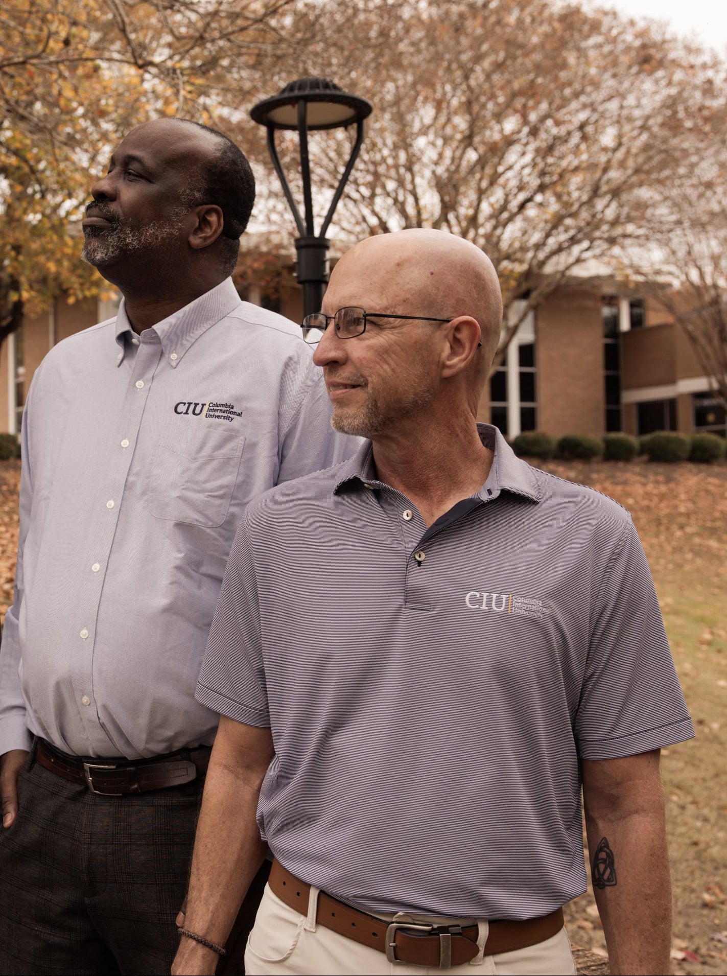 Two men wearing shirts with a CIU logo outdoors.