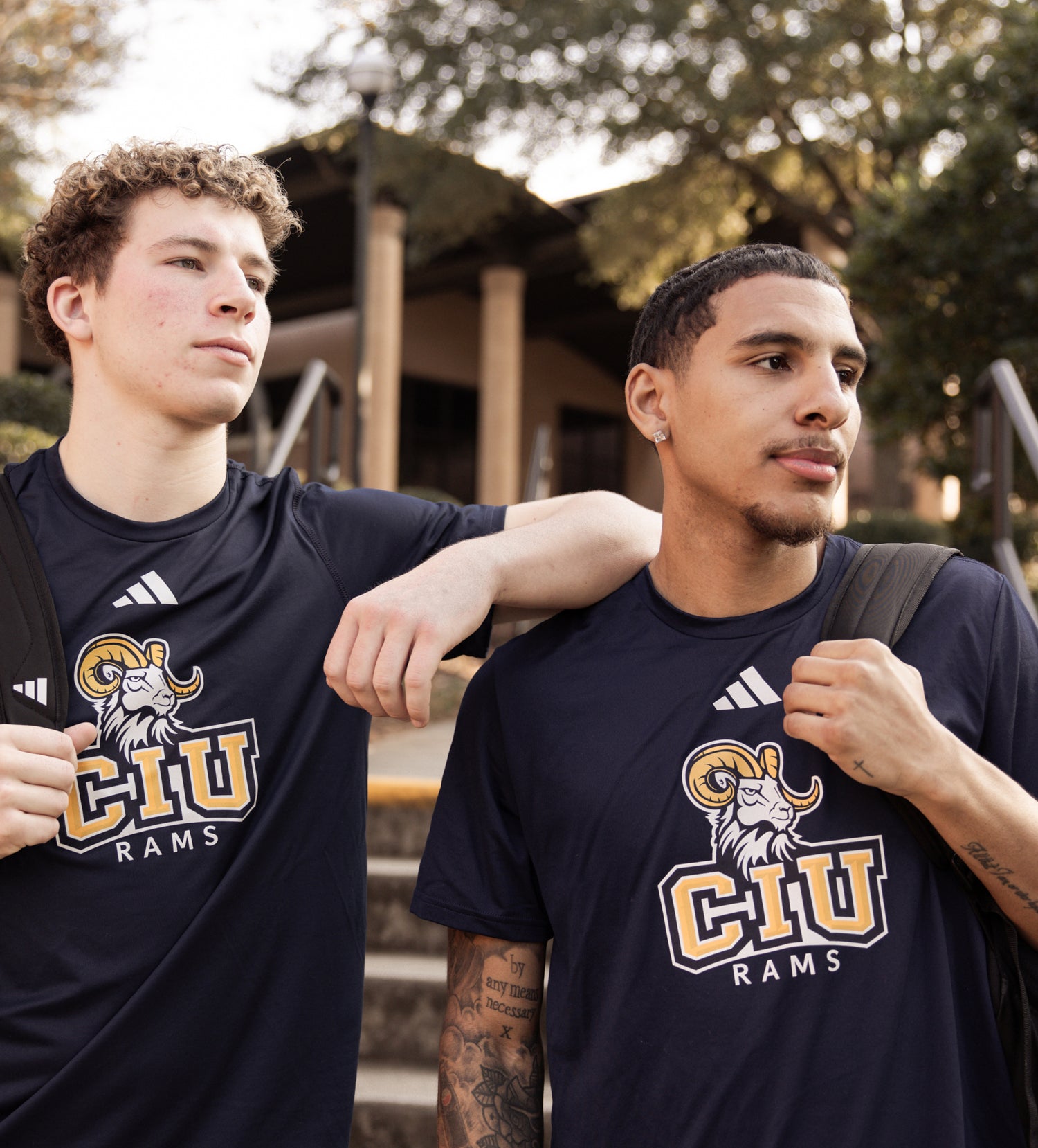 Two men wearing navy blue t-shirts with CIU Rams logo outdoors.