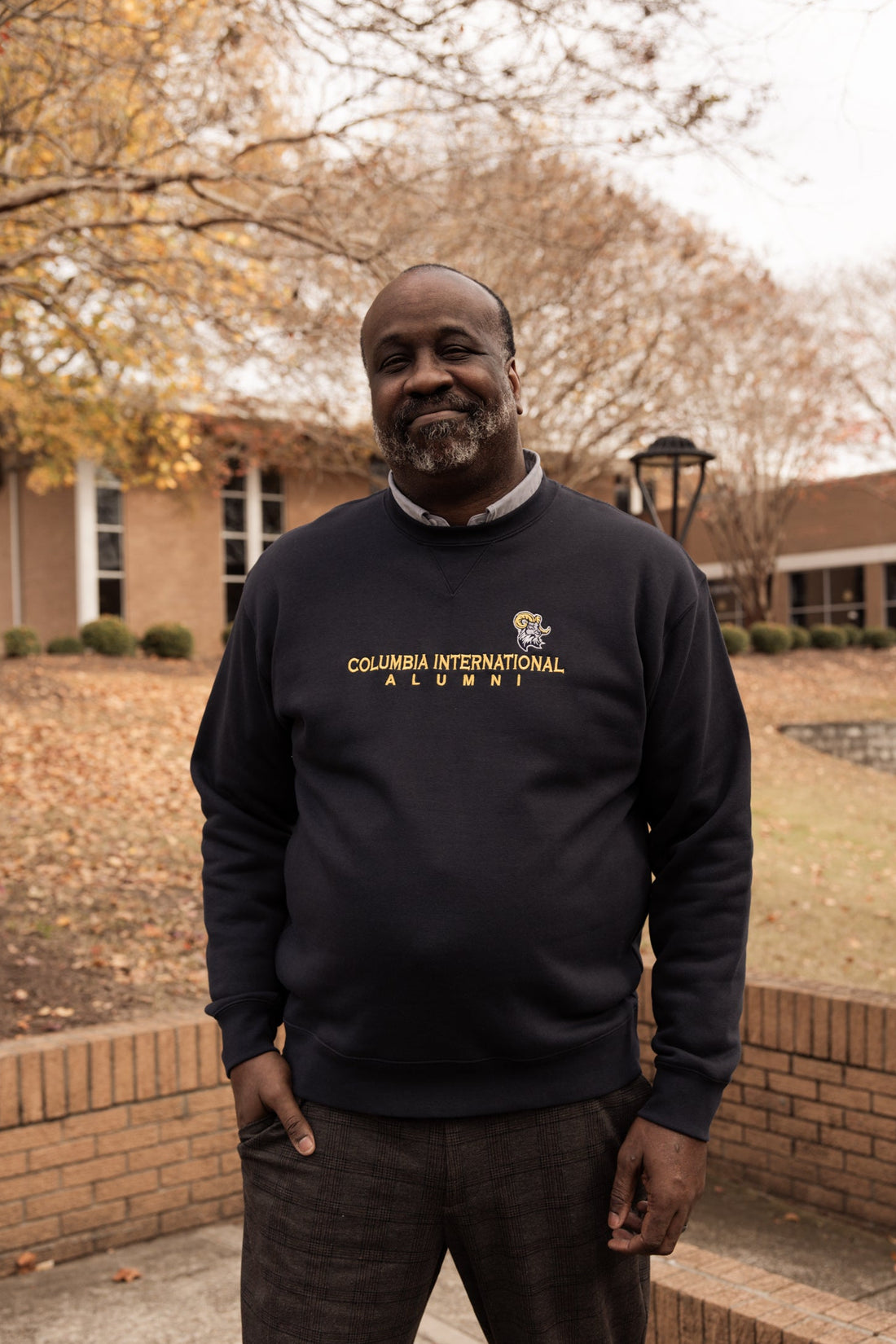 Man wearing a Columbia International Alumni sweatshirt standing outdoors.