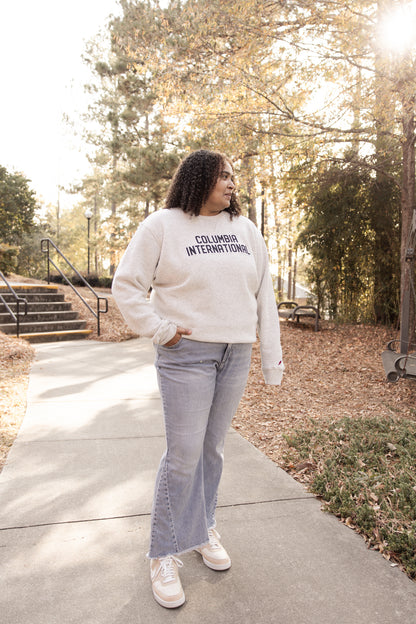 Woman wearing a cream sweatshirt with &