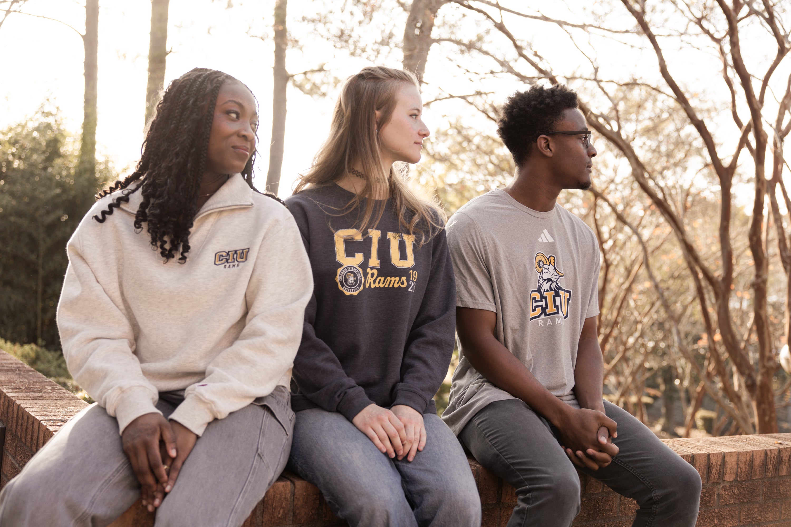 Three people sitting outdoors wearing CIU merch.