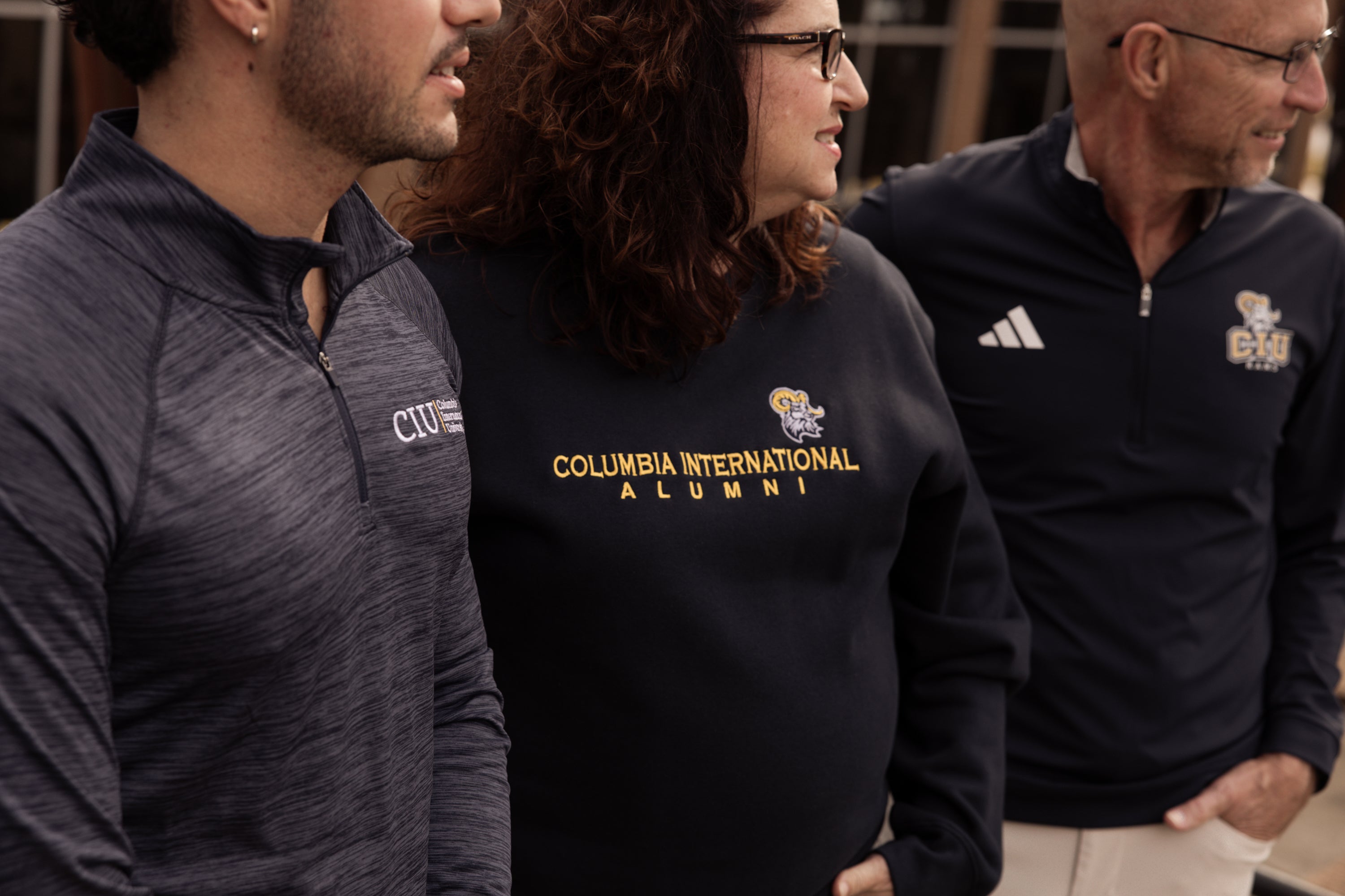 Three people standing side by side, all wearing a variety of &