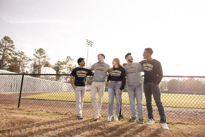 Five students wearing Columbia International University merch standing near a baseball field.